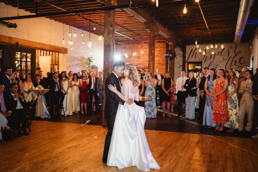 Party guests fill a warm-lit industrial event space while celebrating on the dance floor.