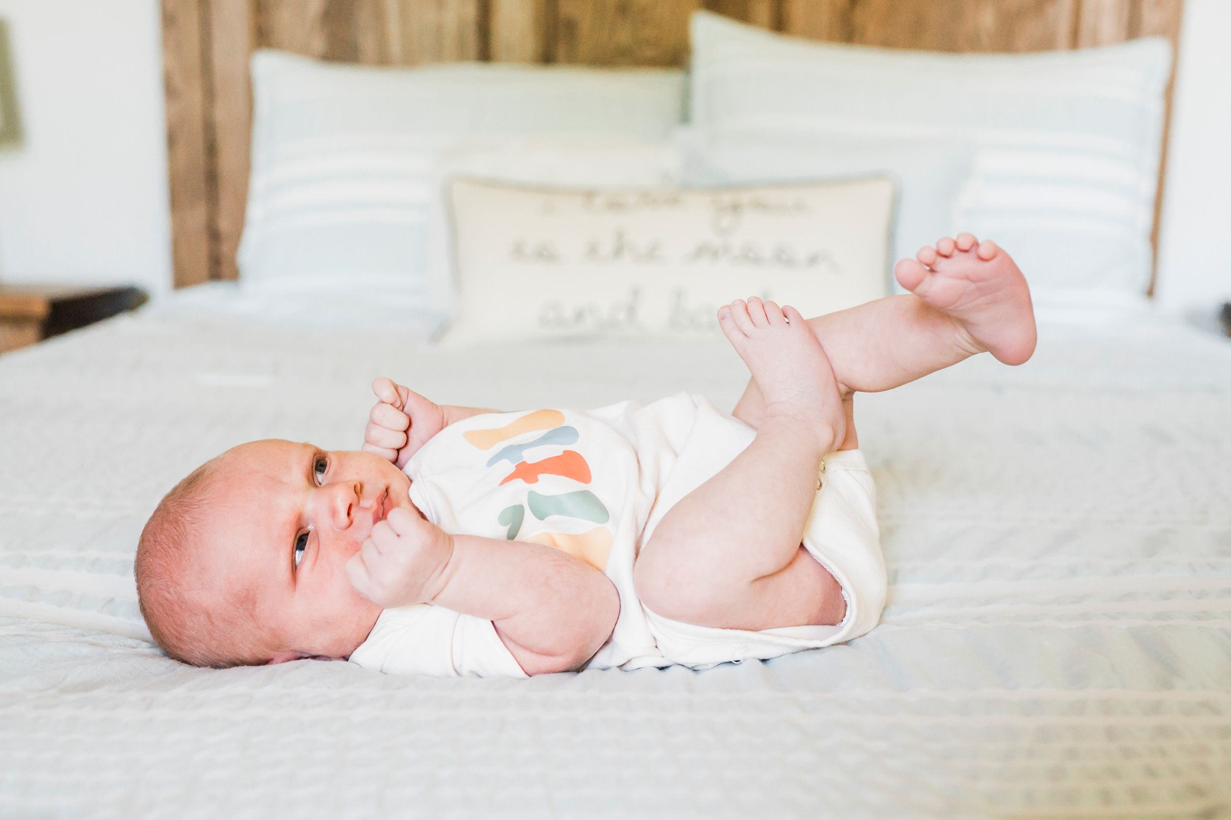 Baby lying on white bedding in a series of candid poses showing movement and playfulness.
