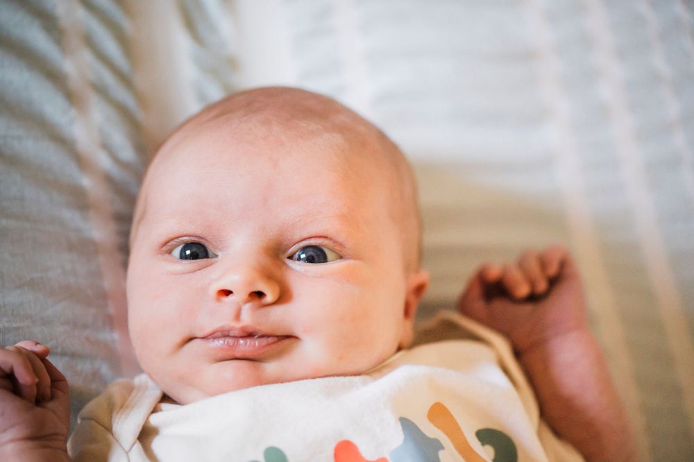 Close-up shots of infant on white bedding showing various facial expressions.