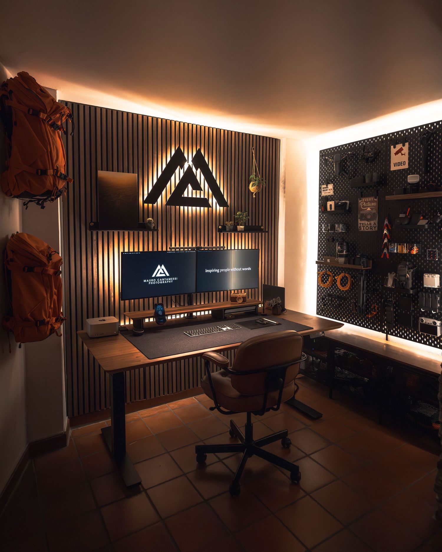 A dimly lit home office setup with warm LED ambient lighting and black acoustic panels on the walls for sound treatment.