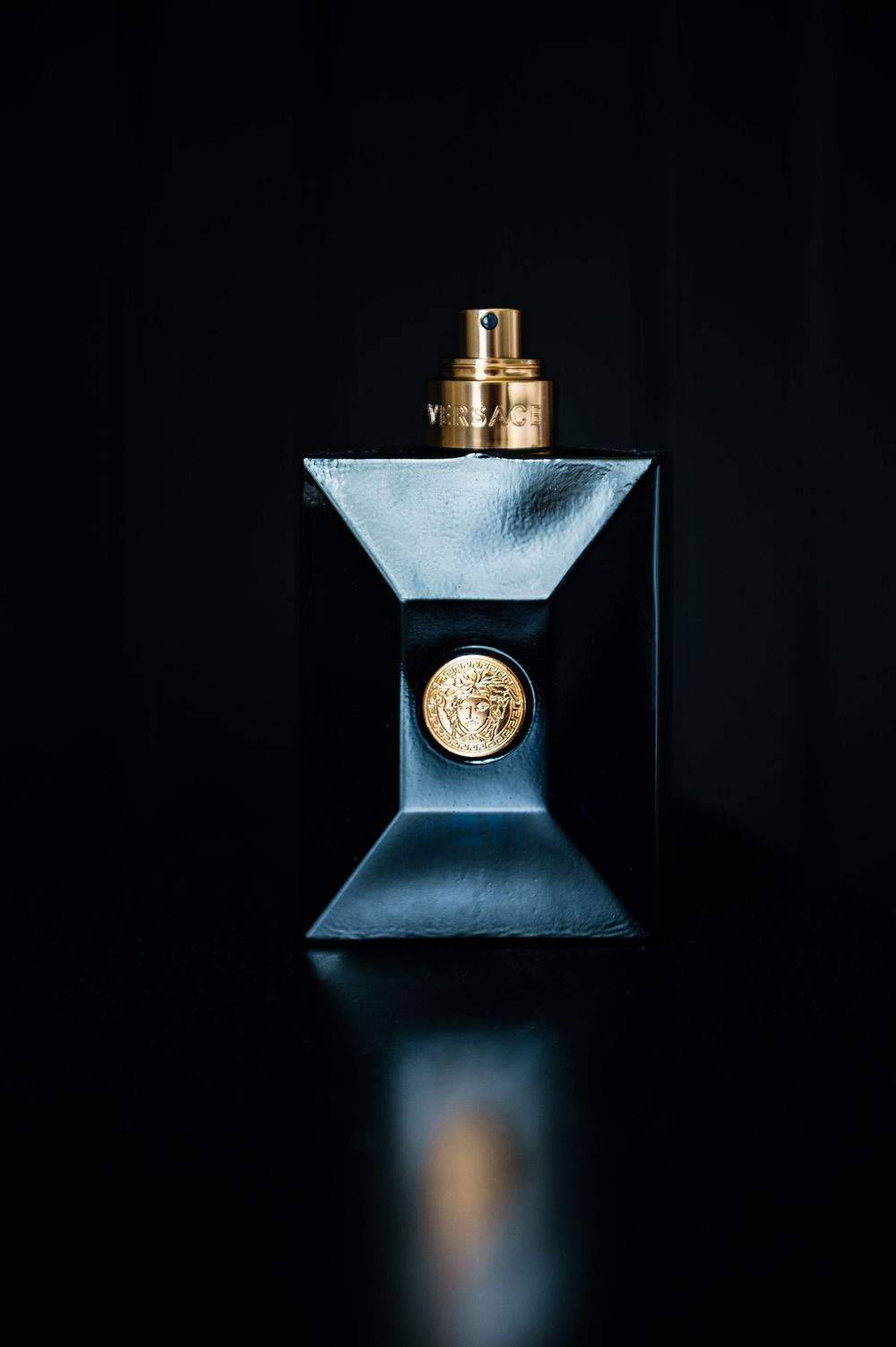 Elegant blue perfume bottle with gold accents against dark background.