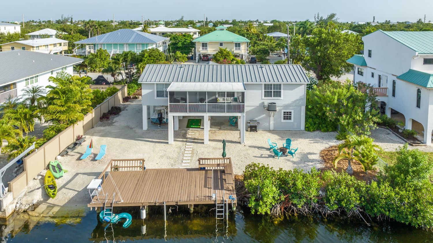 Aerial view of waterfront homes and docks in a tropical residential area.