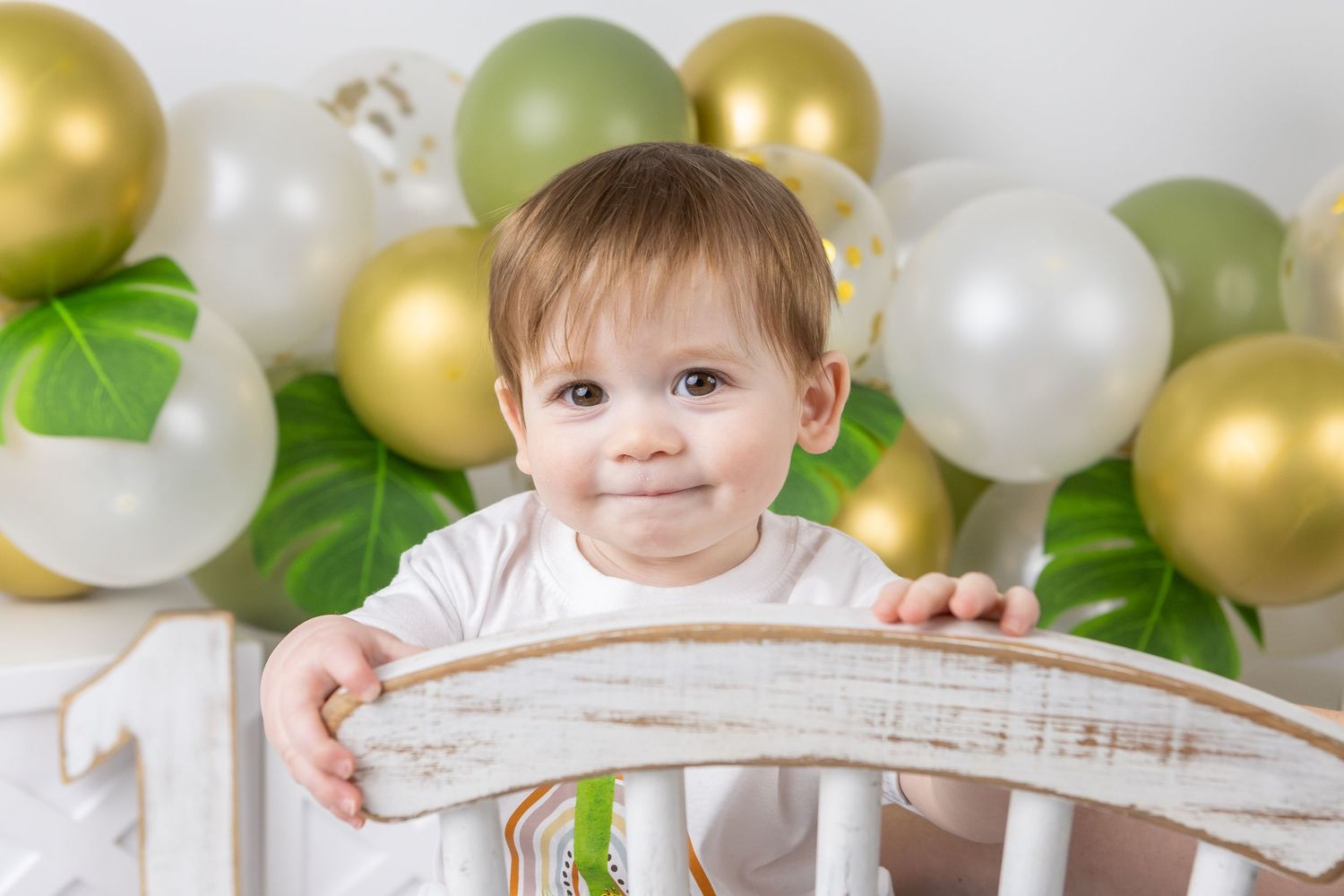 Green and gold balloon themed milestone session with white chair prop.