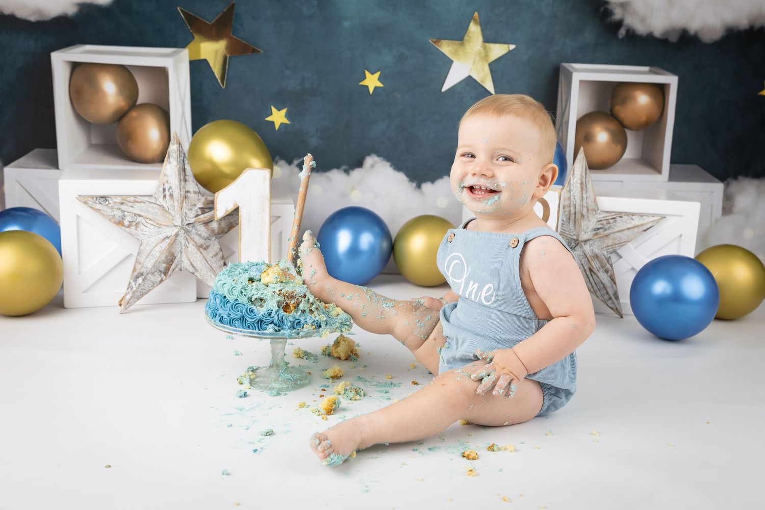Milestone photo session with gold stars, blue balloons and cloud decorations.