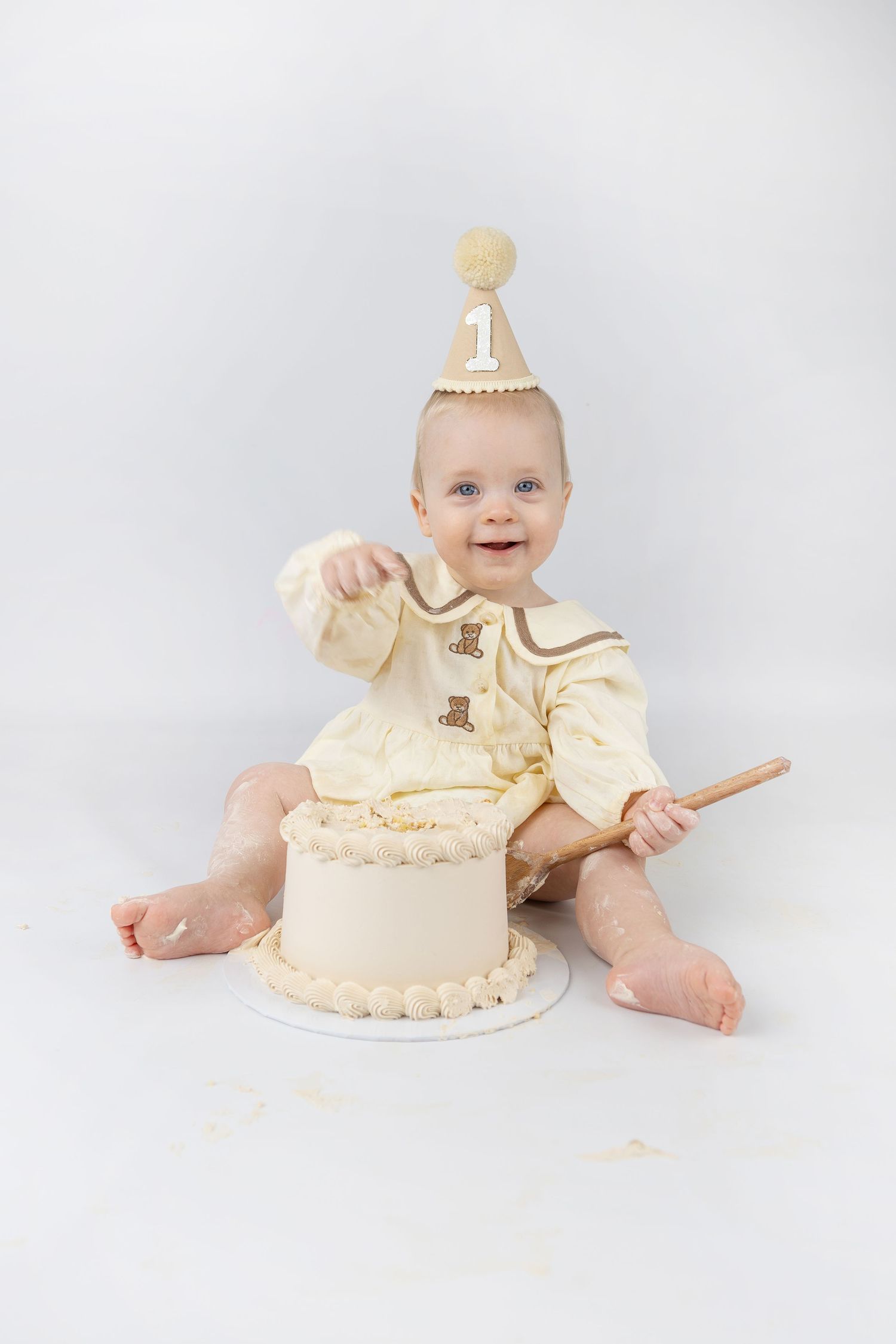 Cream colored cake smash session with elegant first birthday cake and matching outfit.