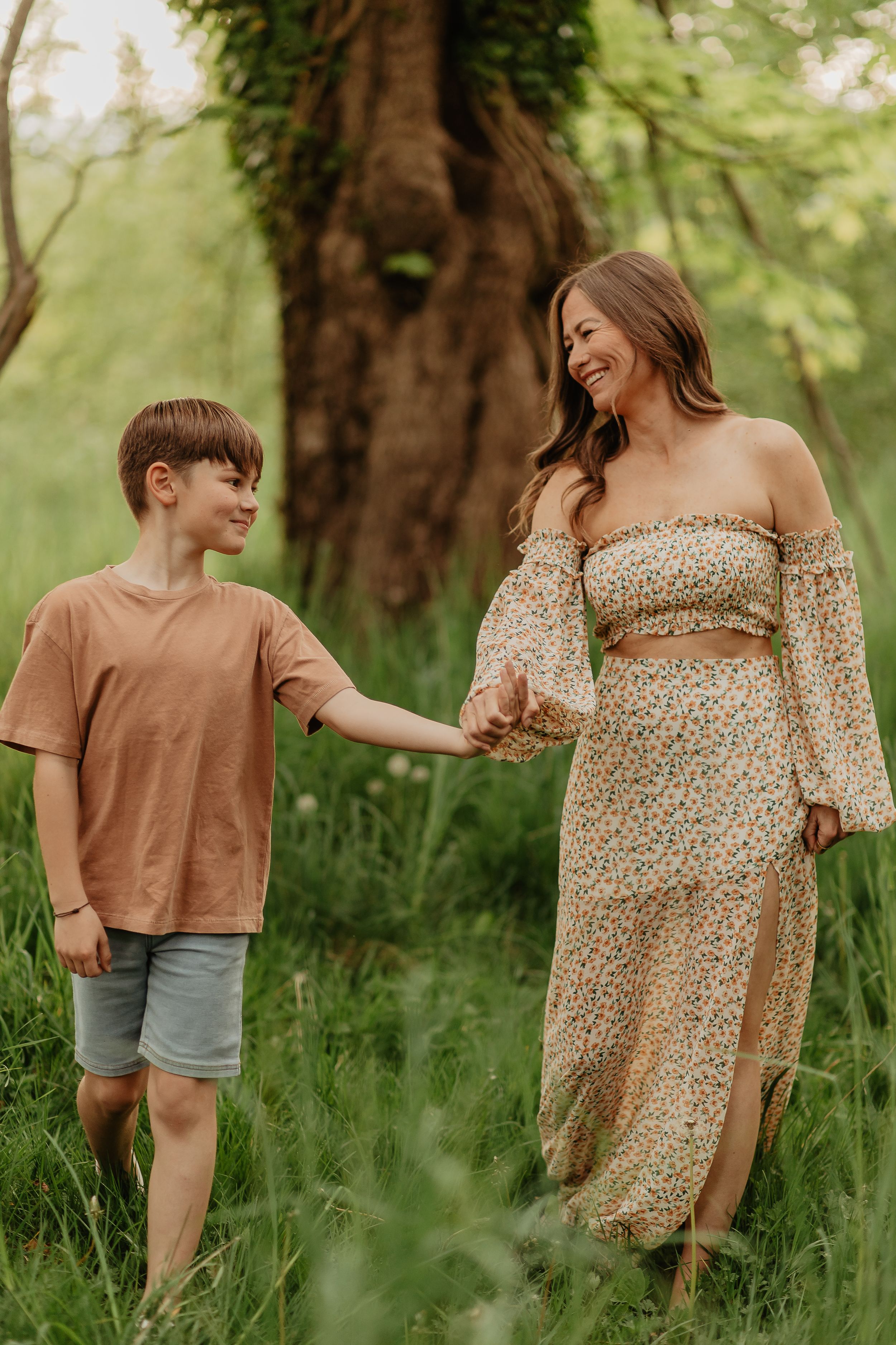 Family walking through lush green grass wearing coordinated earth-toned outfits.