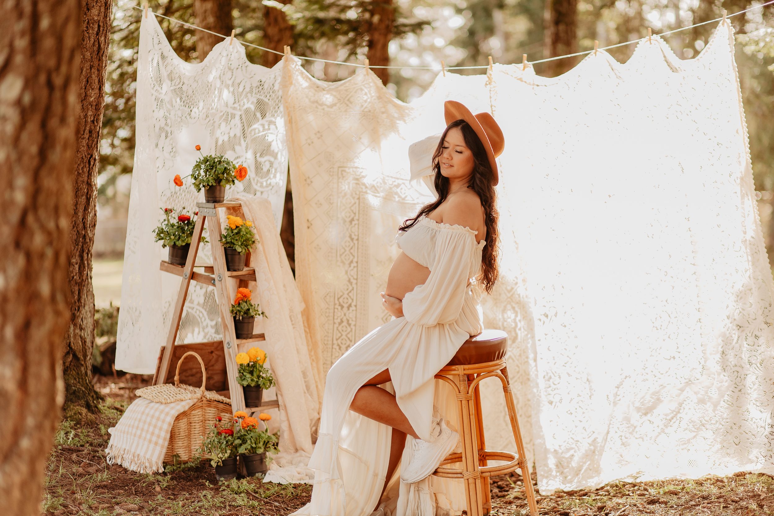 Ethereal maternity photoshoot in a forest setting with white flowing dresses and natural lighting.