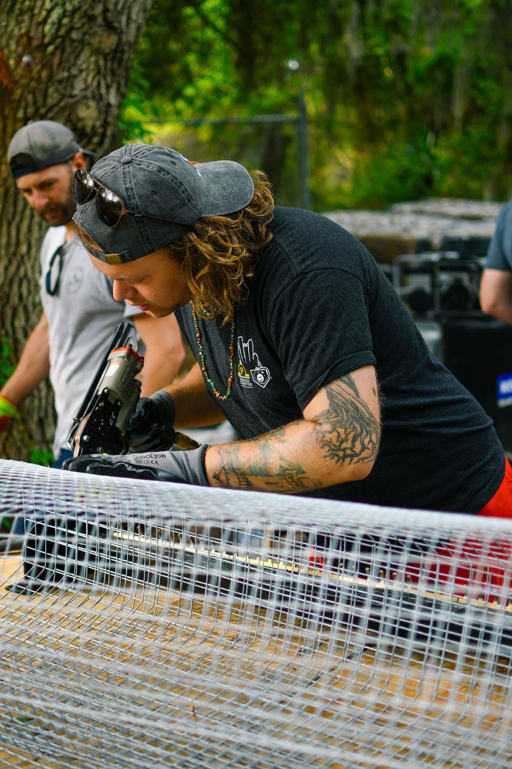 People examining and working on wire mesh equipment outdoors.