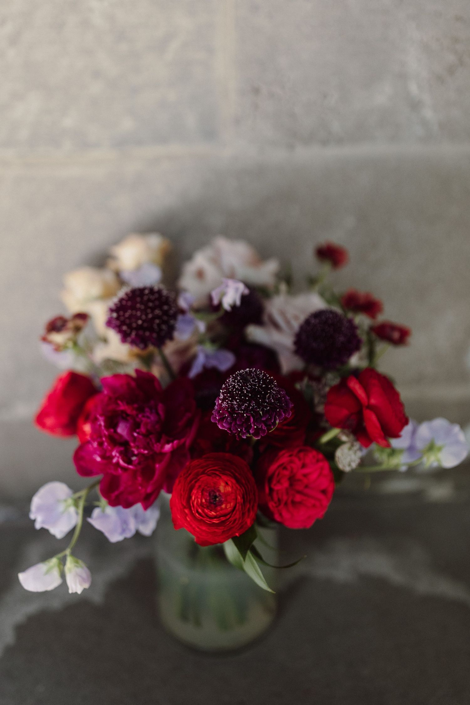 Floral centerpiece with deep red roses and purple blooms.