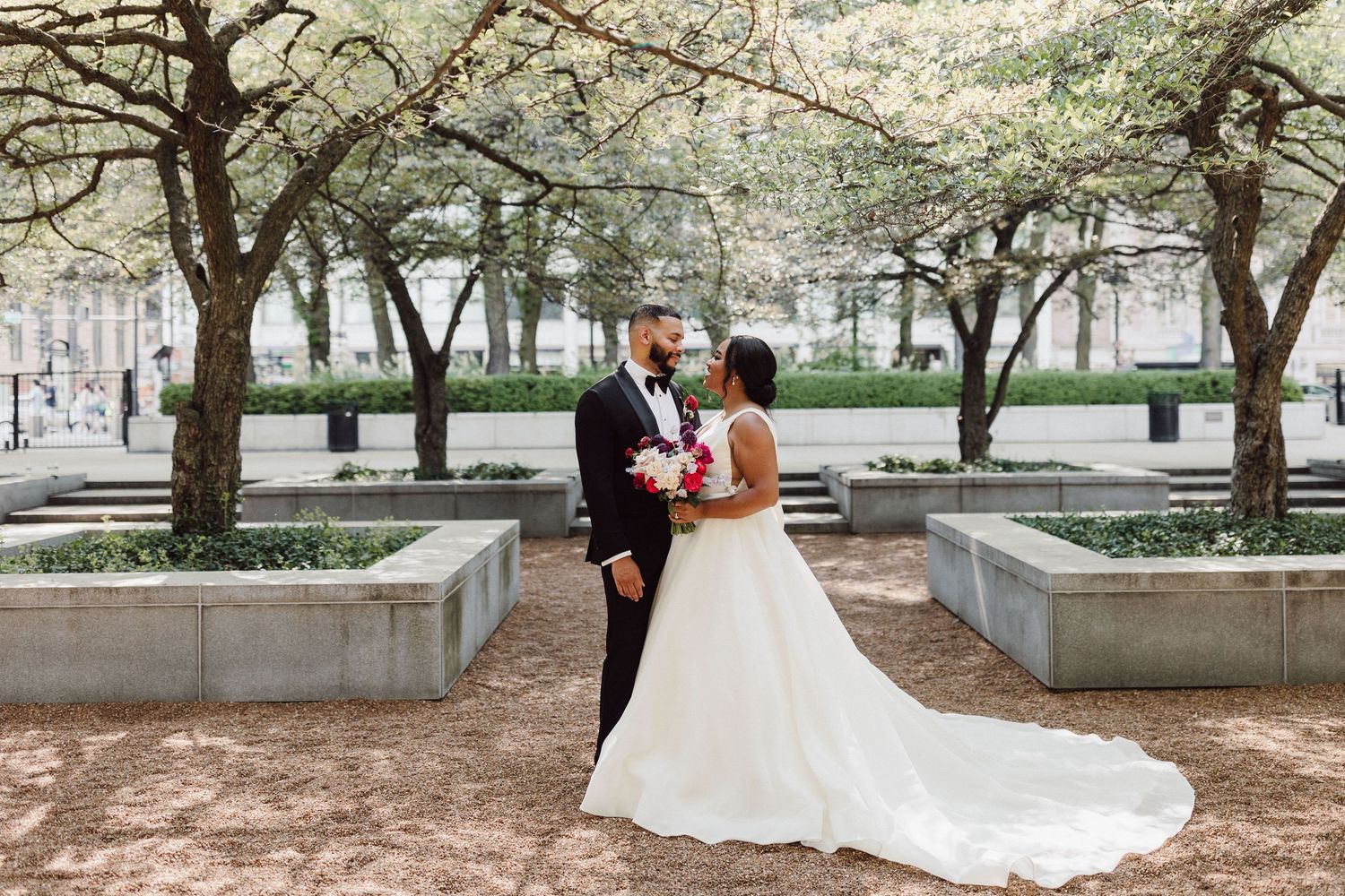 Wedding couple photographed under blooming spring trees in an urban garden.