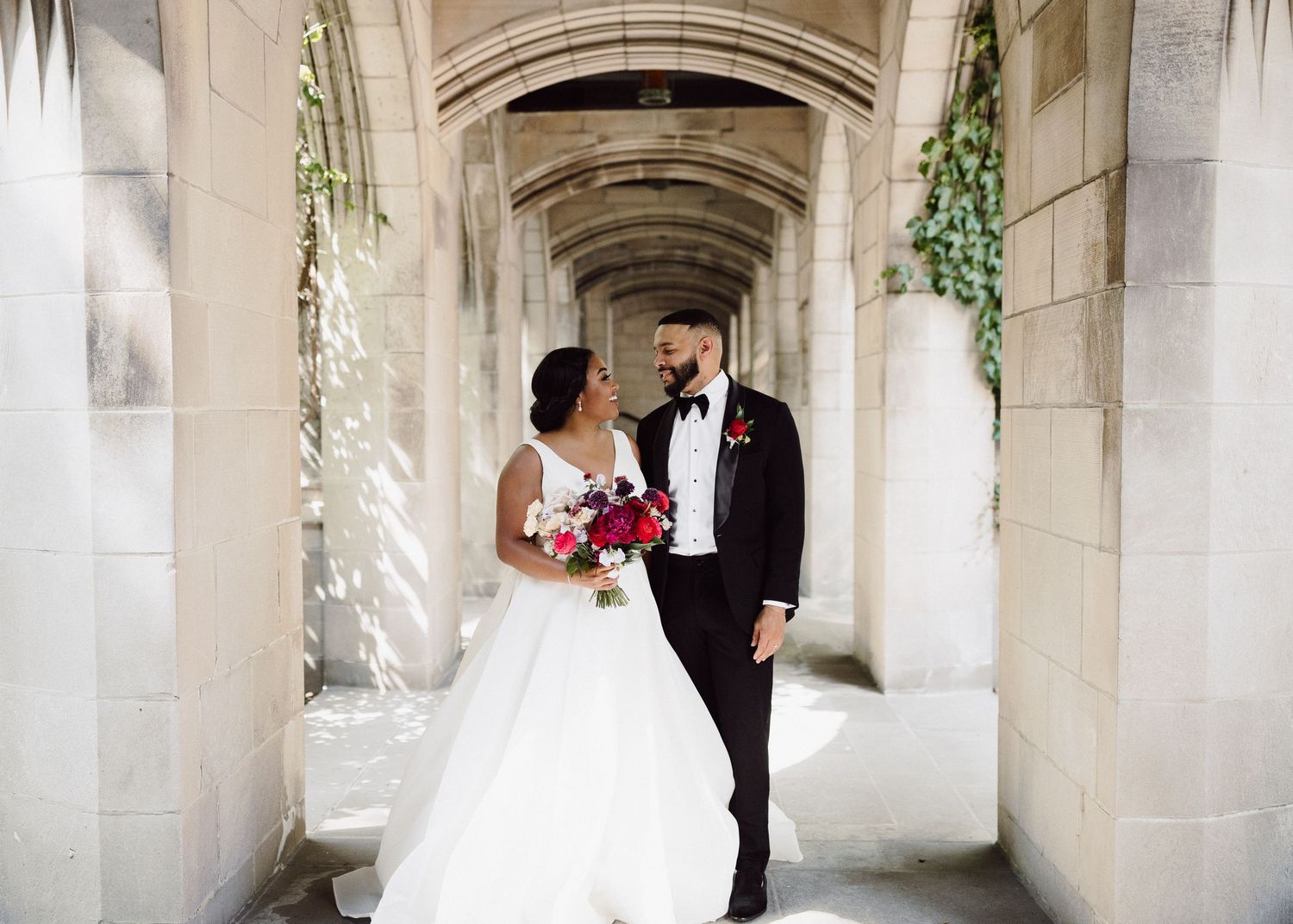 Romantic wedding portrait under stone archway with ivy details.