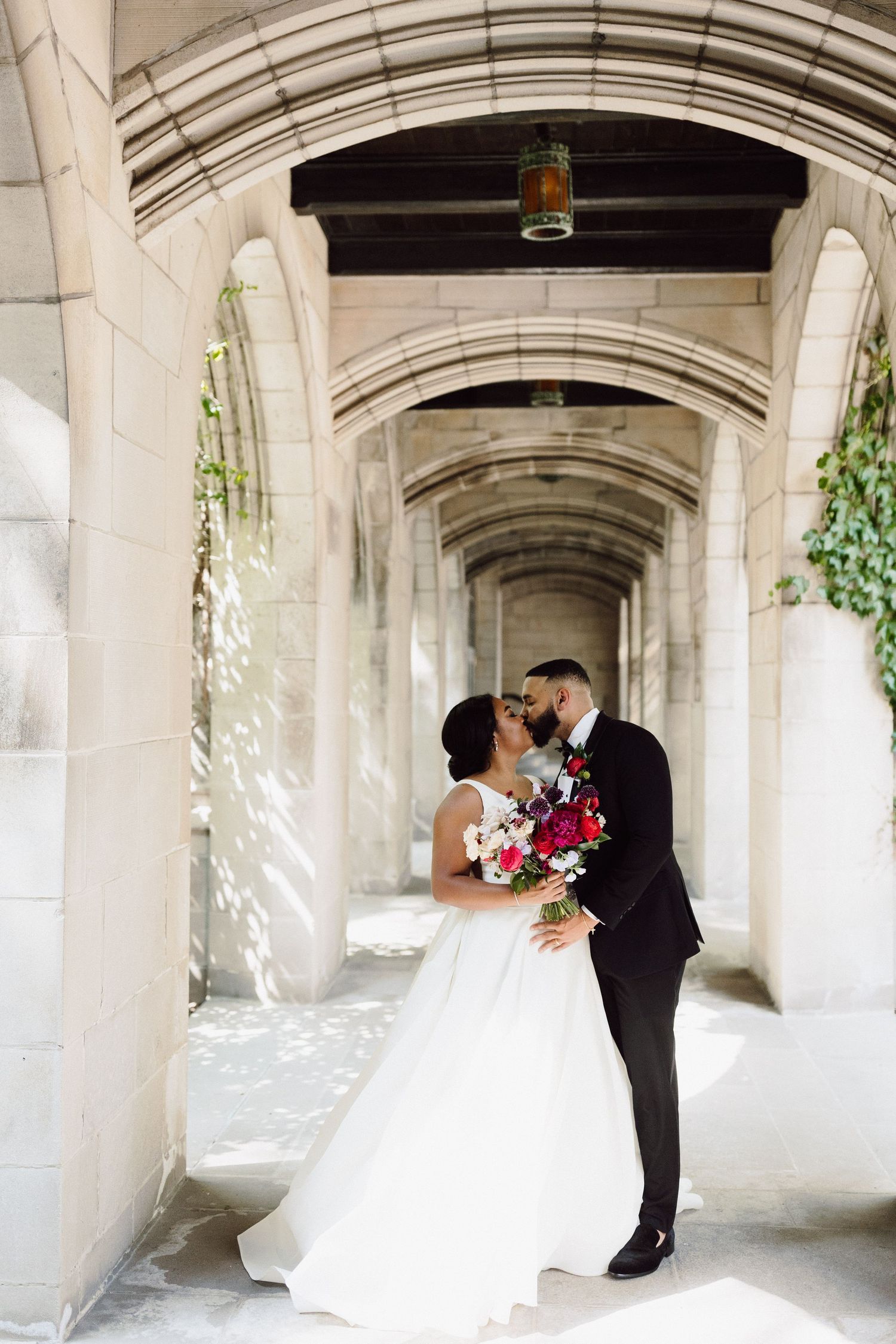 A romantic wedding photo series showing a couple embracing in a stone archway corridor.