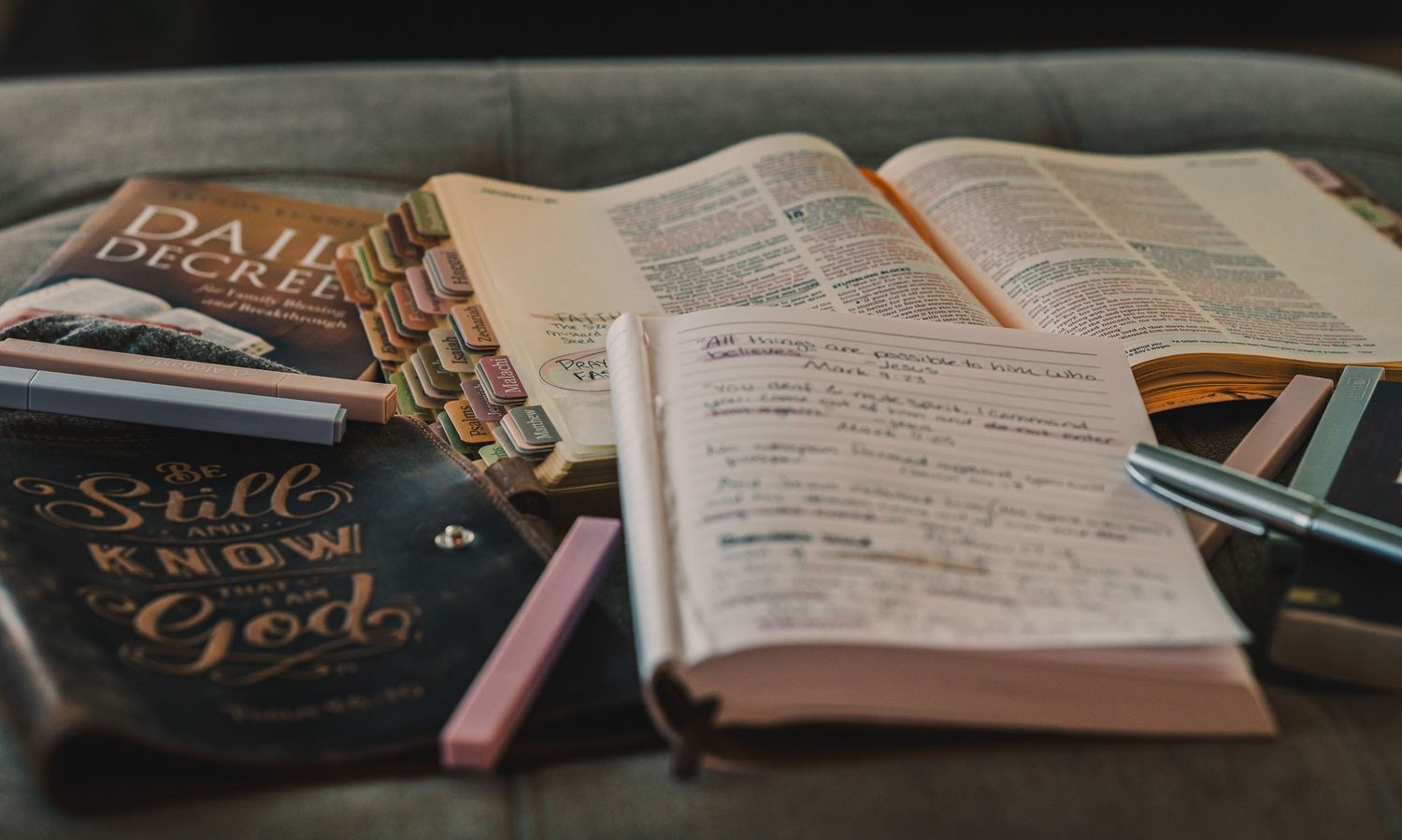 Open notebook with handwritten notes surrounded by study materials and colorful pens on a dark surface.