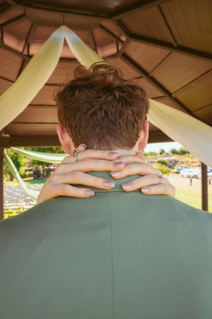 Green outdoor bench seat at a park shelter with hands resting on the backrest.