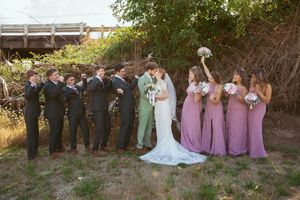 Wedding party lineup shows bridesmaids in lavender dresses and groomsmen in sage suits against natural backdrop.