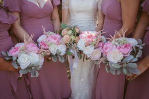Bridal and bridesmaid bouquets with pink and white peonies, roses and eucalyptus against mauve dresses.