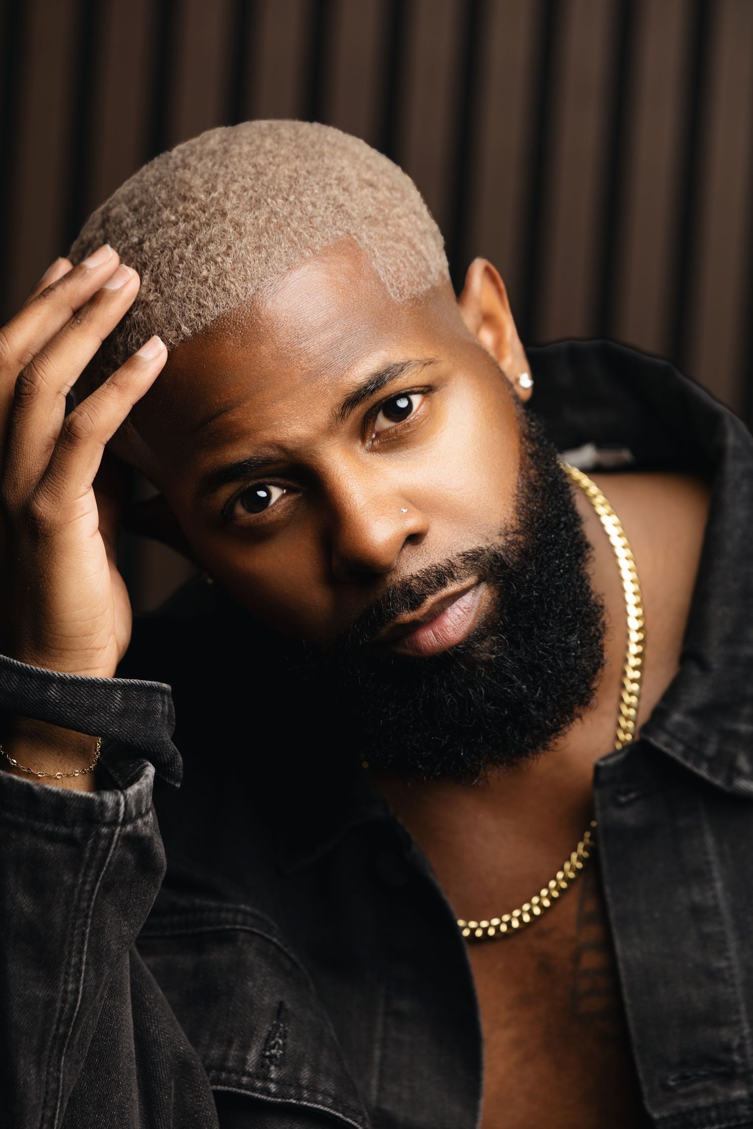 Professional studio portraits of a bearded person in a black denim jacket striking different poses against dark background.