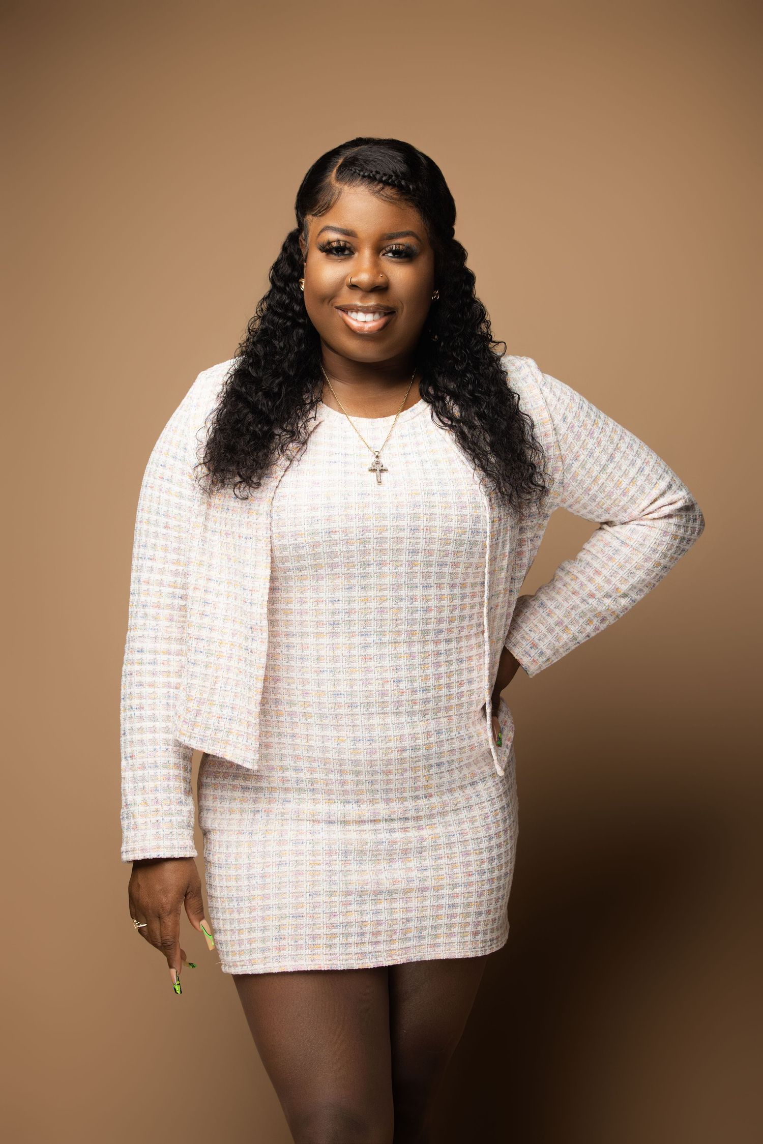 Person wearing white textured sweater poses confidently against beige background.