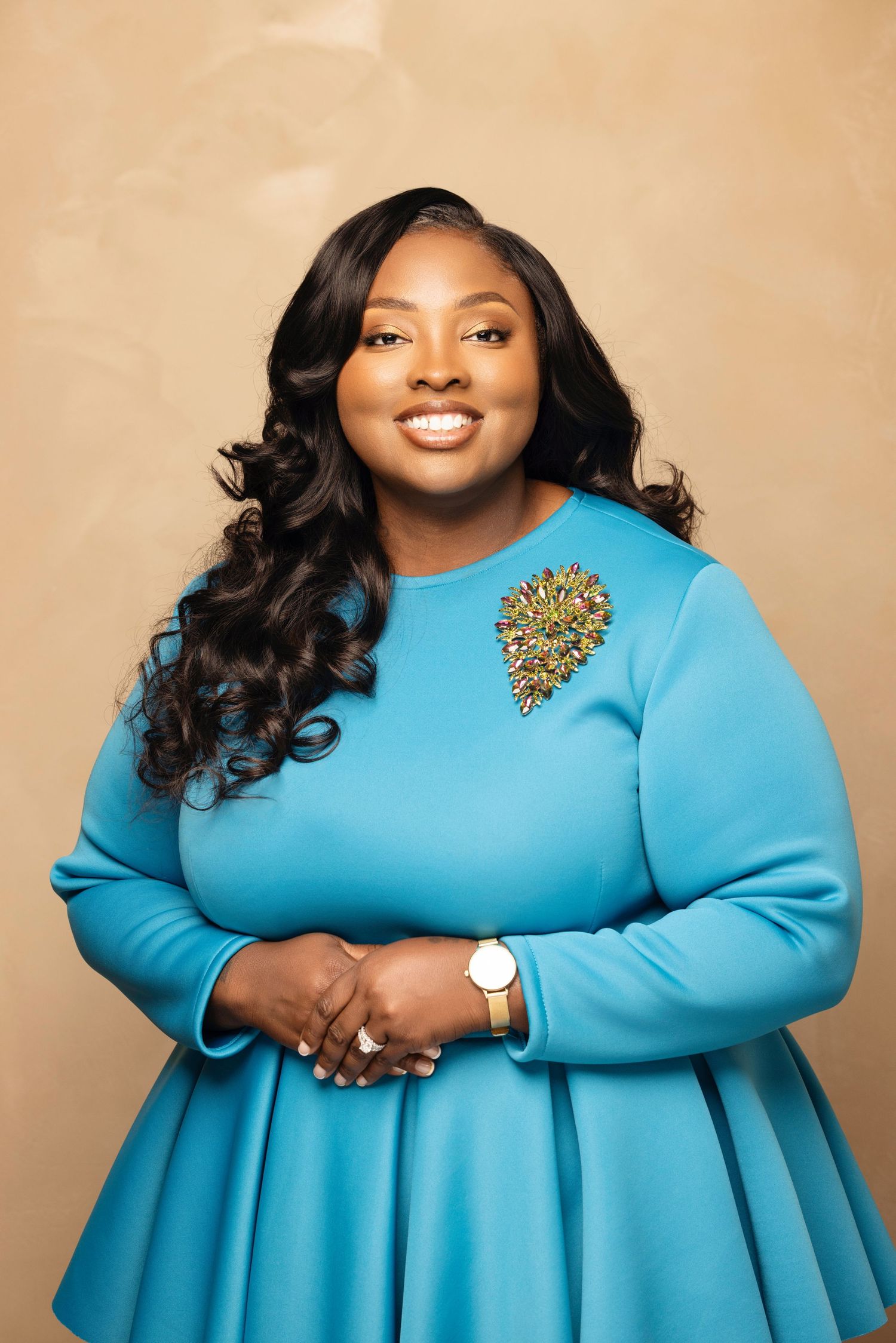 A person in a bright turquoise long sleeve dress poses confidently for a series of professional studio portraits.