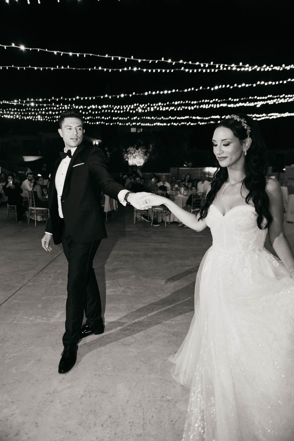Elegant black and white photo sequence capturing a couple dancing at their wedding reception under string lights.