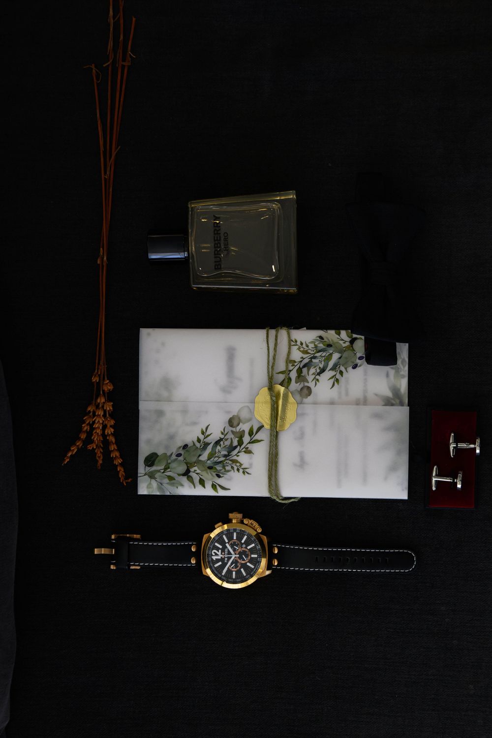 Artistic still life arrangement featuring a wristwatch and decorative elements against a dark background.