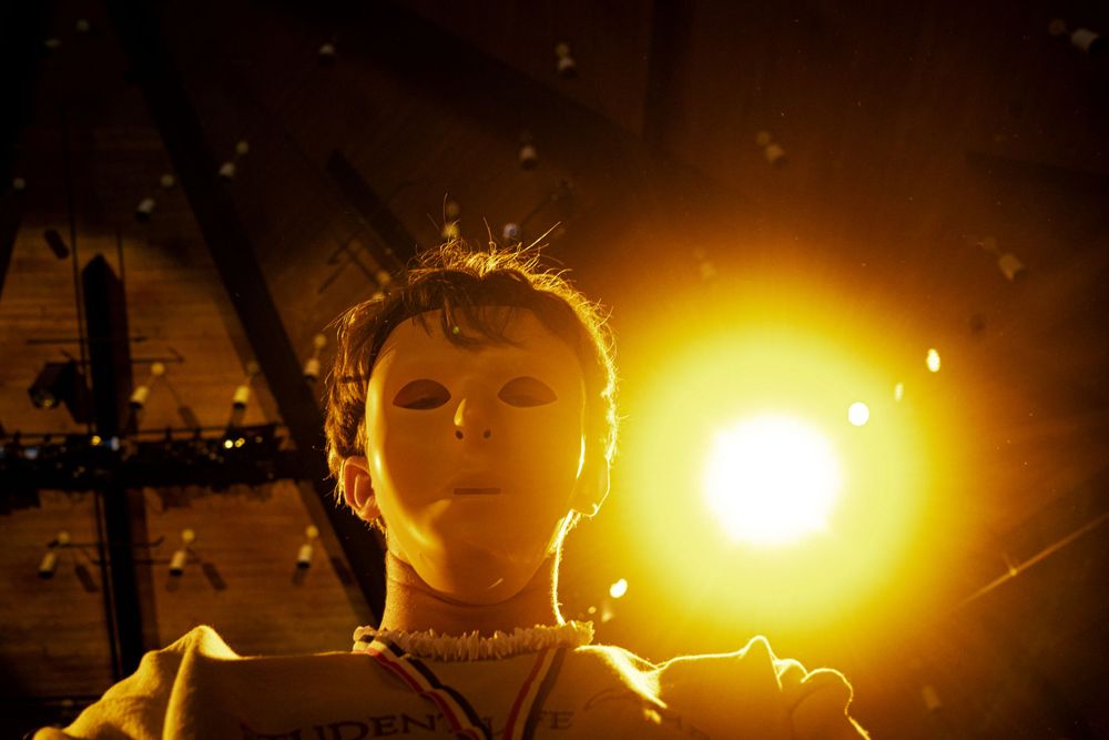Child illuminated by warm golden light with insects flying around in darkness.