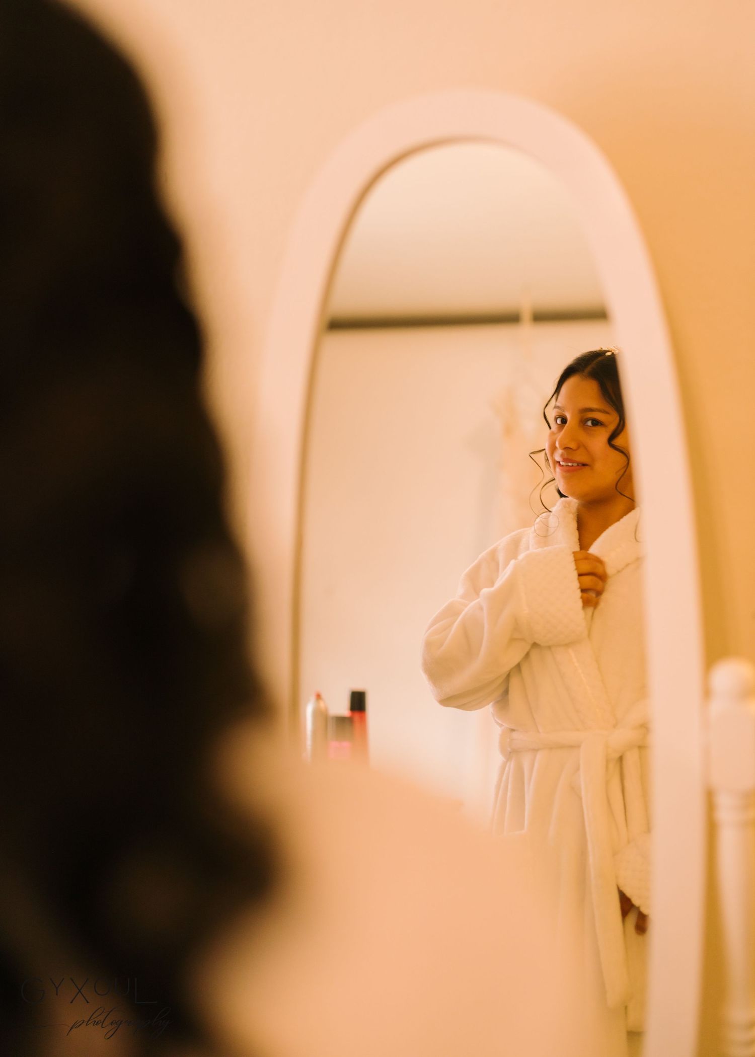 Artistic mirror reflection shot in warm tones showing preparation in white robe.