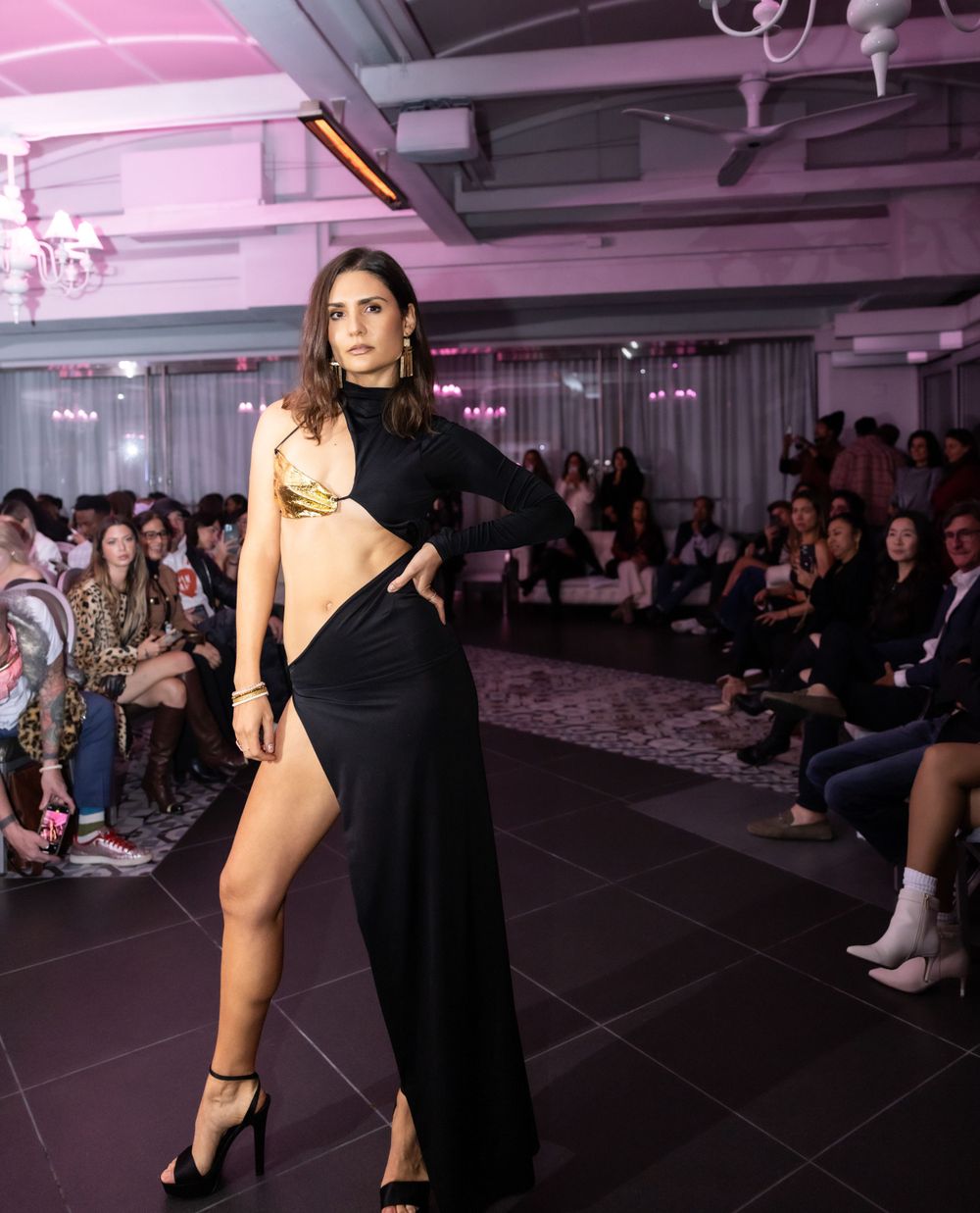 Dramatic black cutout evening dress with high slit presented at fashion show.