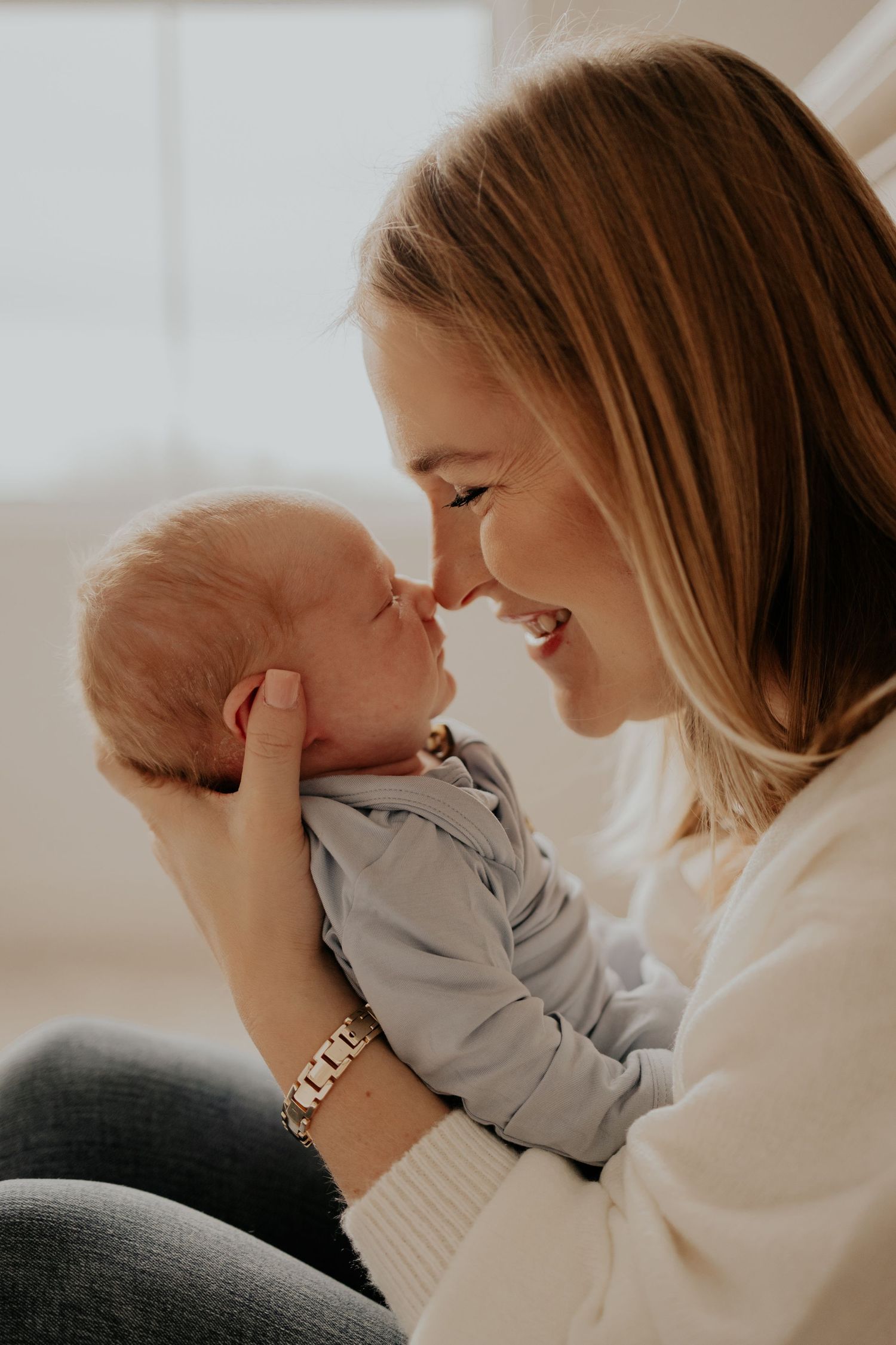 A tender moment between mother and baby as they share an intimate nose-to-nose connection in warm lighting.