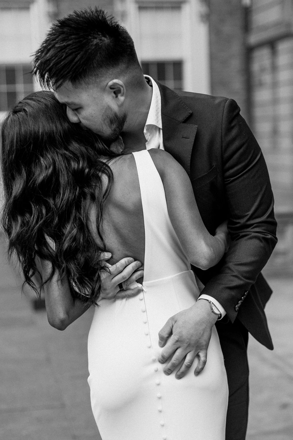 Intimate black and white portrait of couple embracing in formal wedding attire.