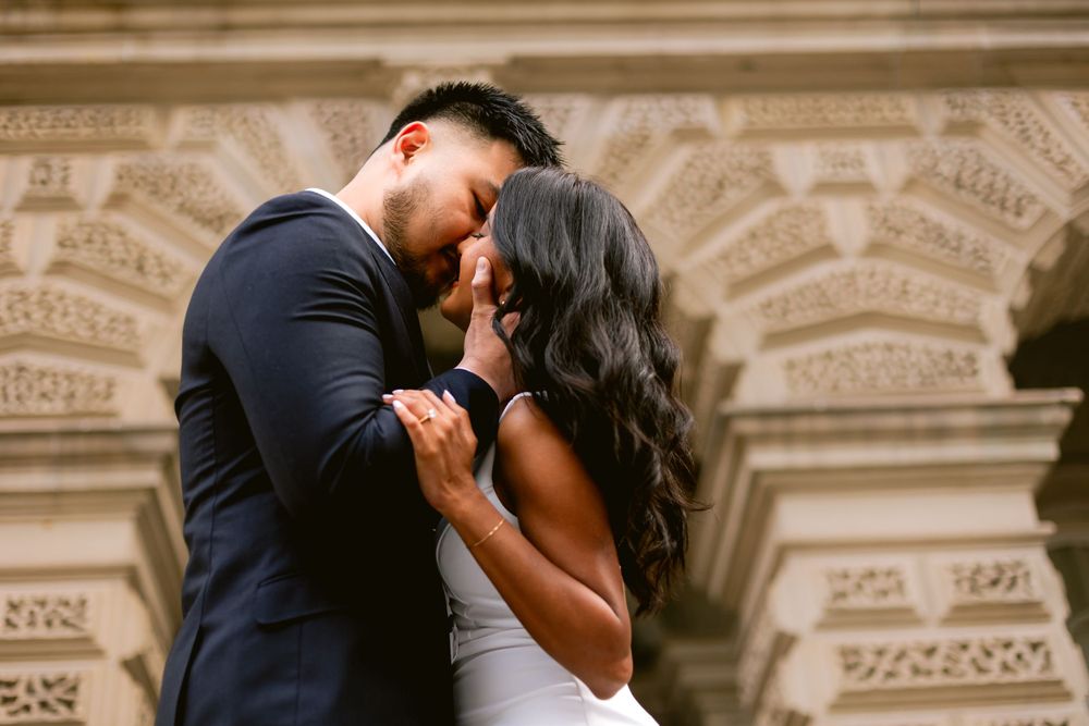 A romantic moment captured between a couple against an ornate architectural backdrop.