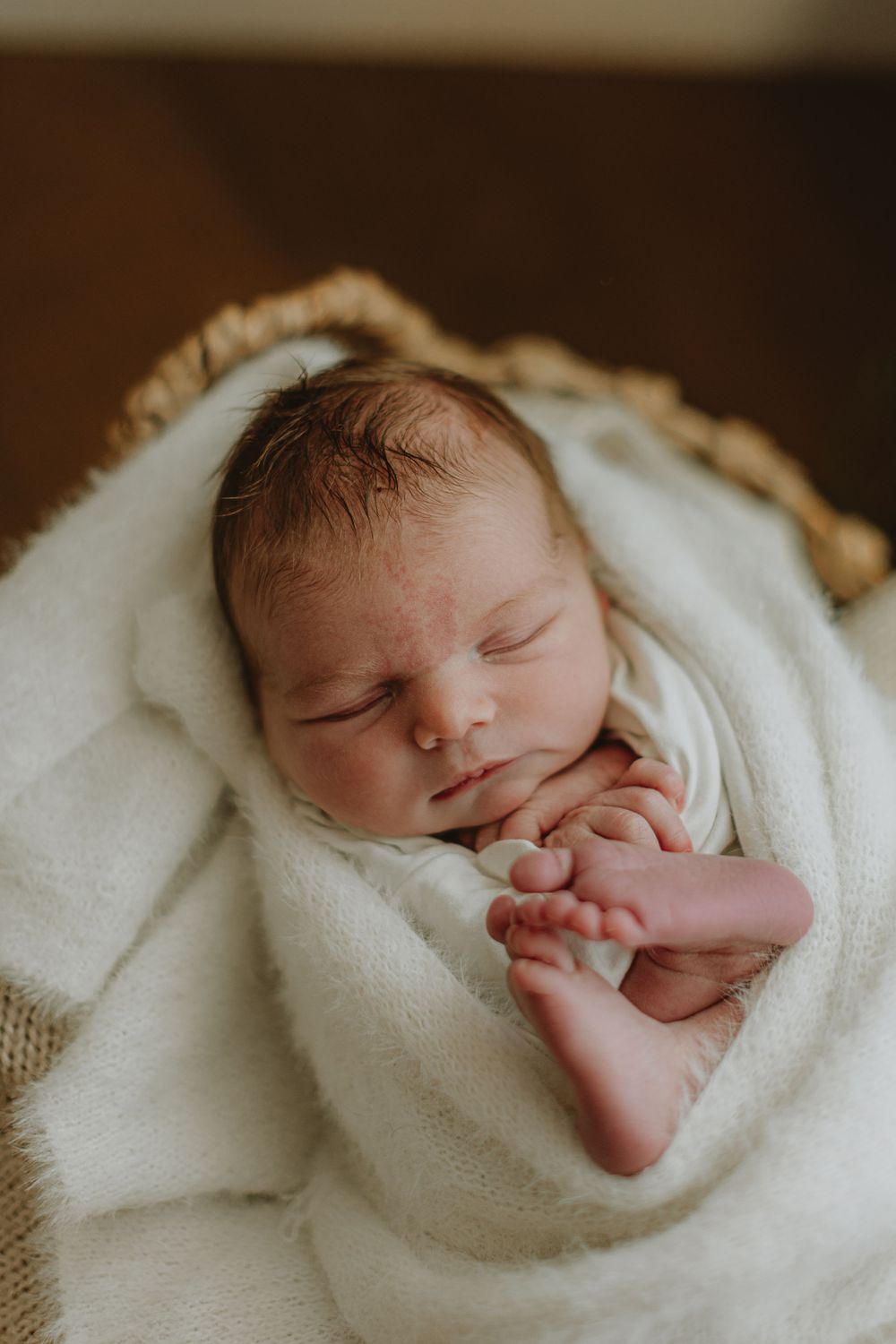 Close-up of sleeping newborn baby swaddled in white blanket showing peaceful expression.