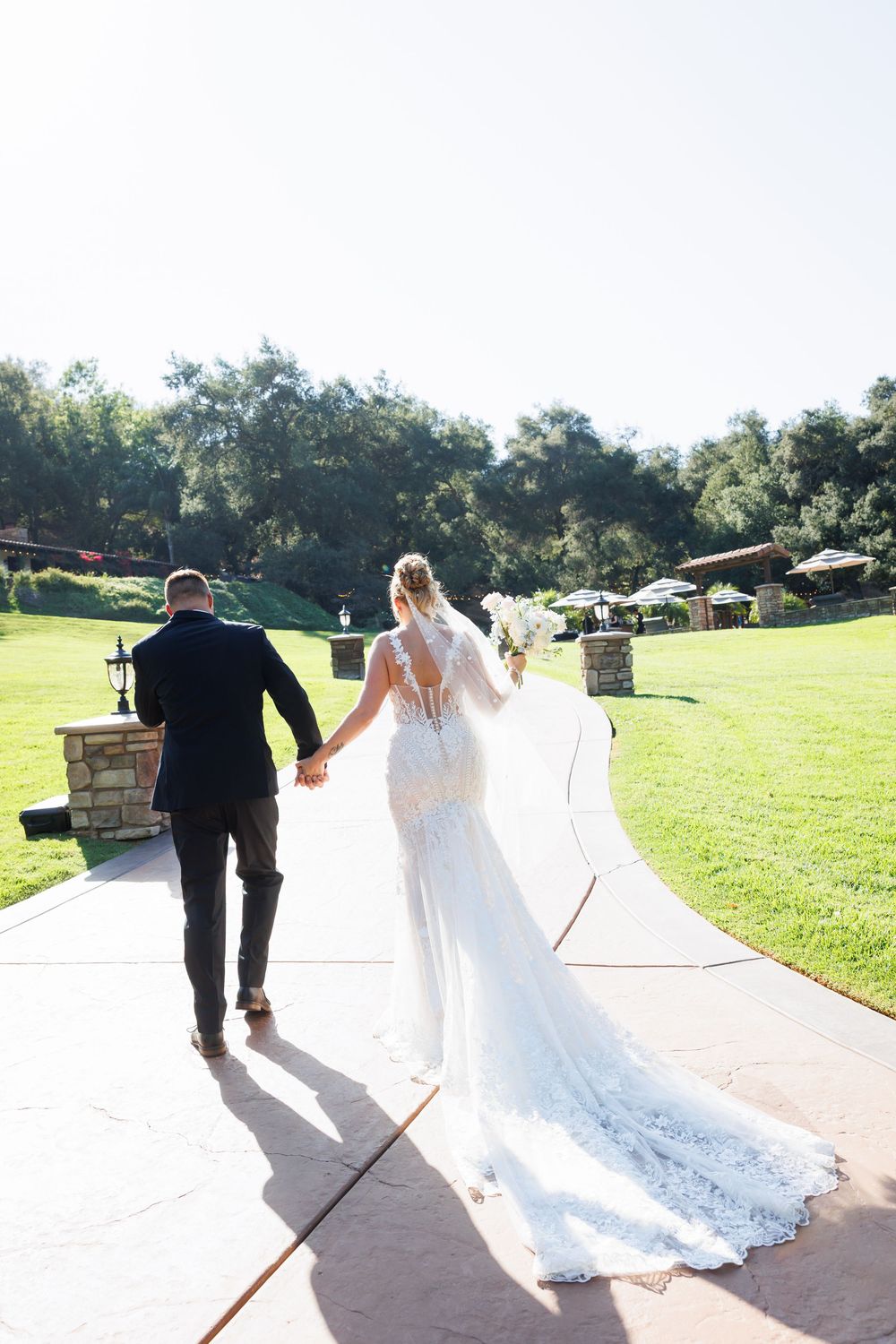 A couple in wedding attire walking down a path while holding hands, shown in four sequential photos.