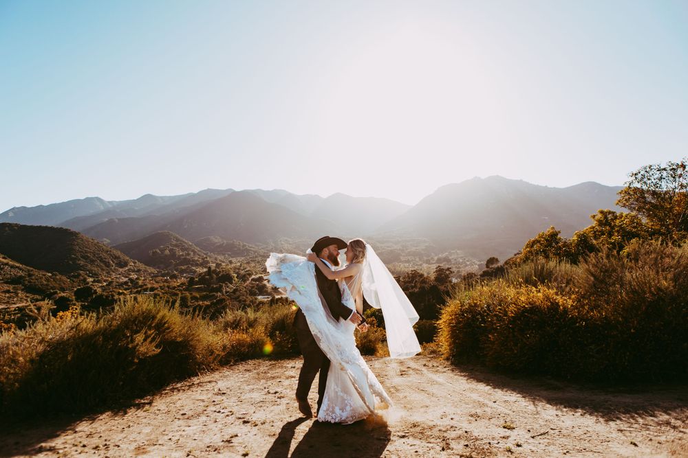 Long dress flowing in the wind against mountain backdrop with golden sunlight at Circle Oak Ranch Wedding.