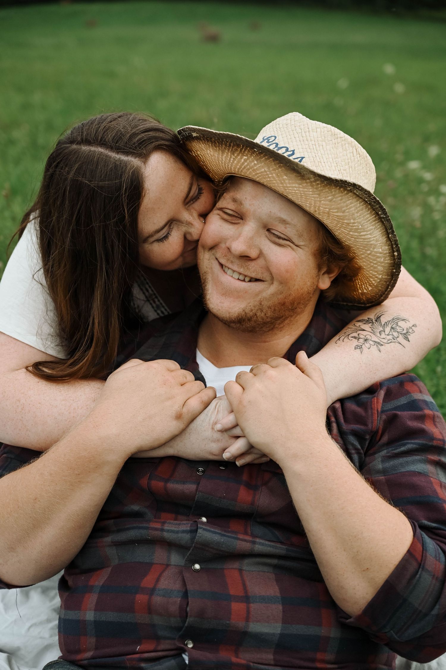 A tender moment shared between a couple outdoors as they embrace on green grass.