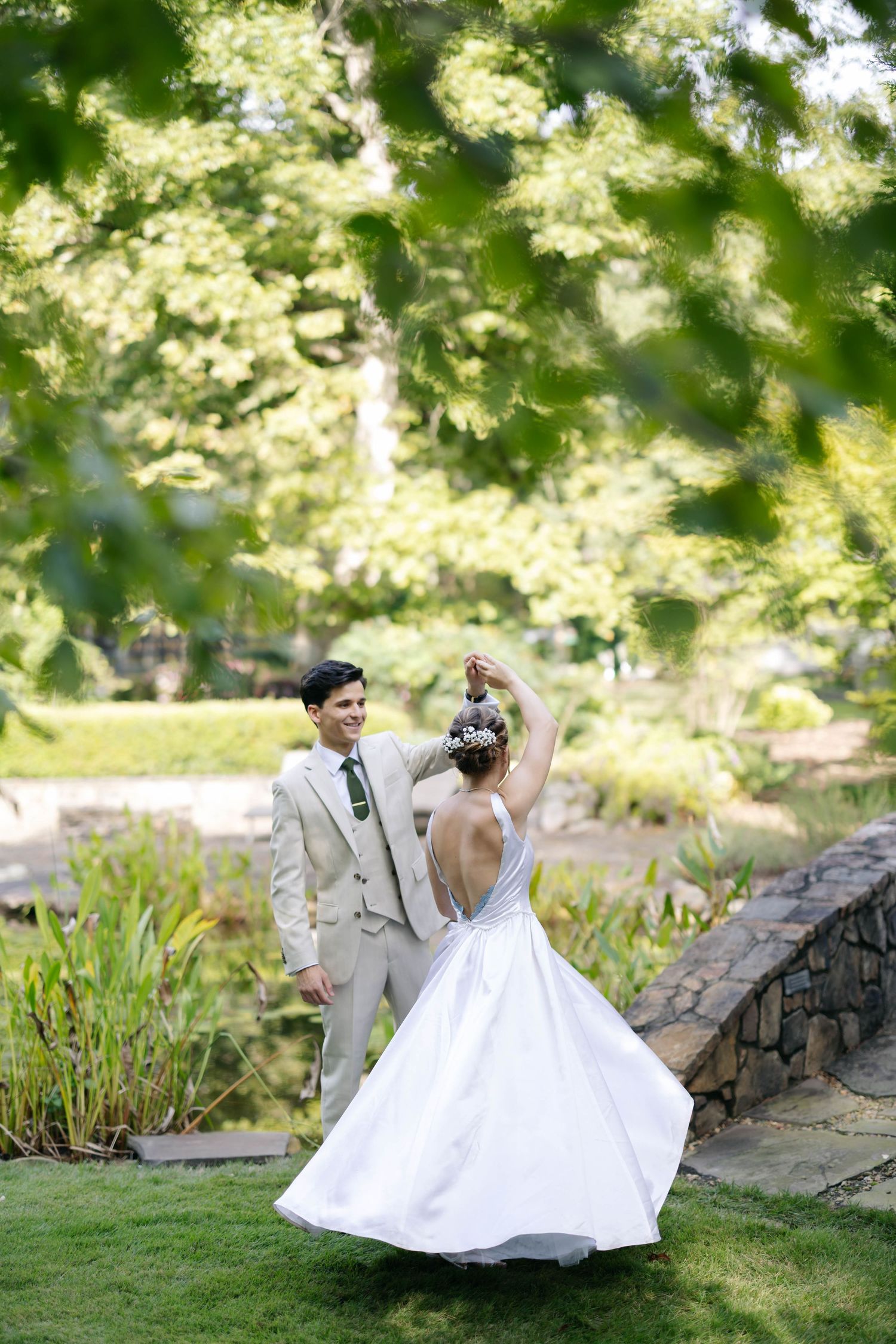 A romantic garden wedding photoshoot with stone walls and sunlit foliage in the background.