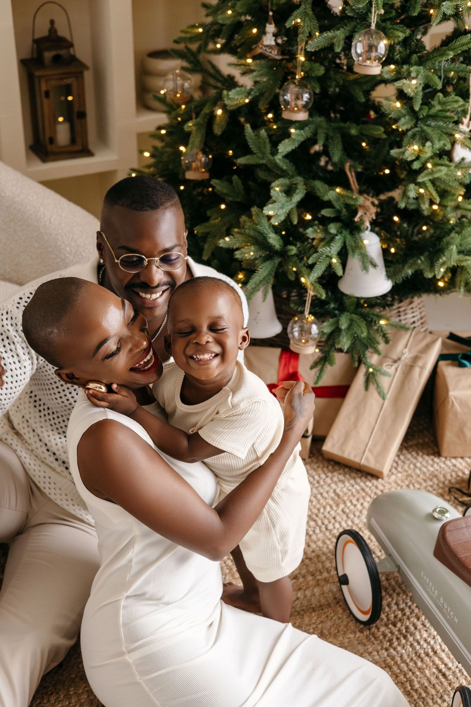A happy family shares joyful moments together while sitting on the floor near a decorated Christmas tree and wrapped presents.