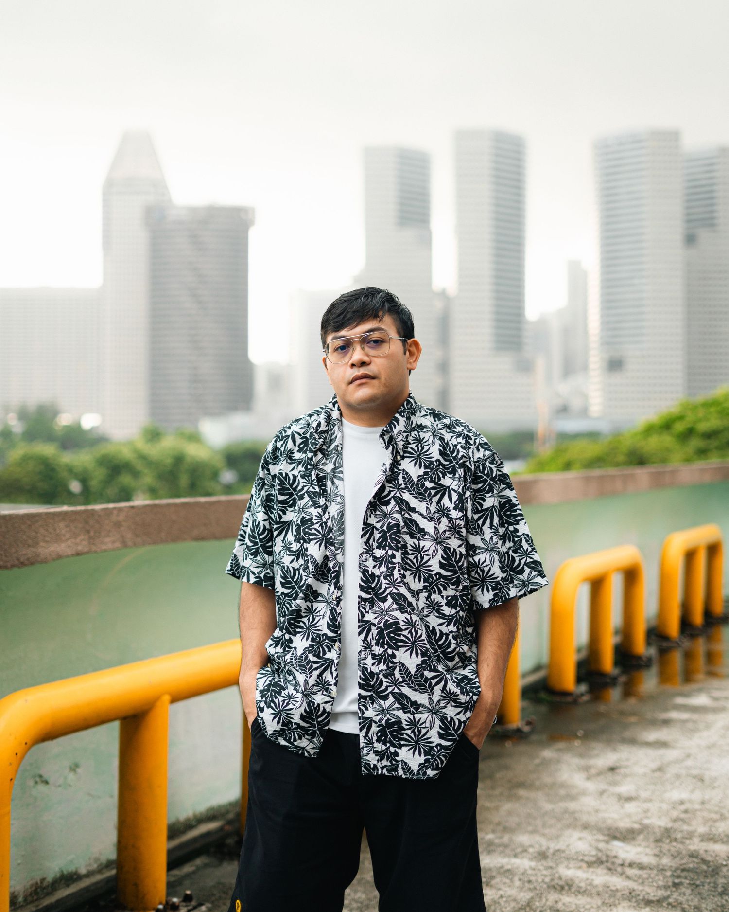 Person in patterned shirt posing against foggy urban skyline backdrop.