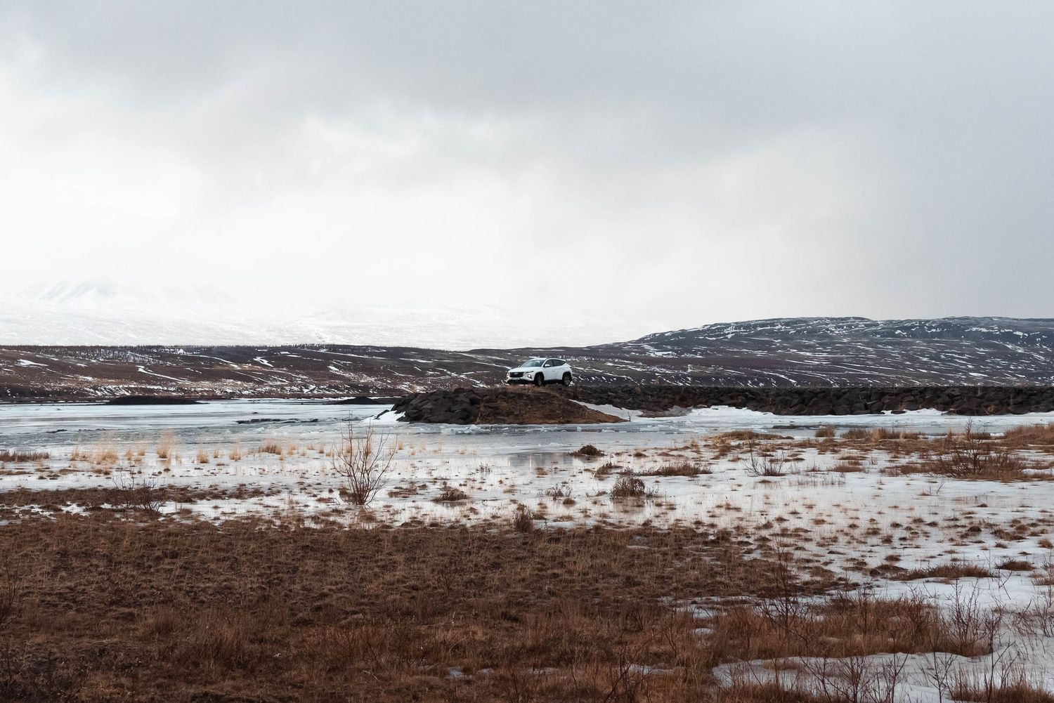Paysage d'hiver enneigé avec un sol aride et un ciel couvert dans une nature sauvage isolée.
