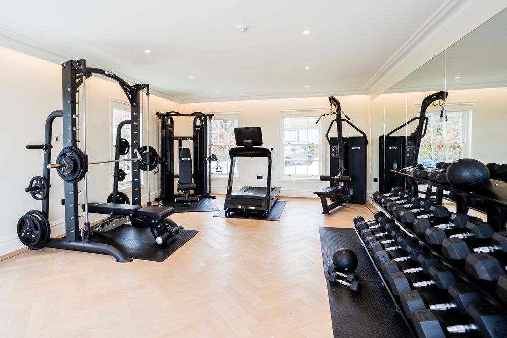 Well-equipped home gym with weight machines, dumbbells, and cardio equipment in a bright space.