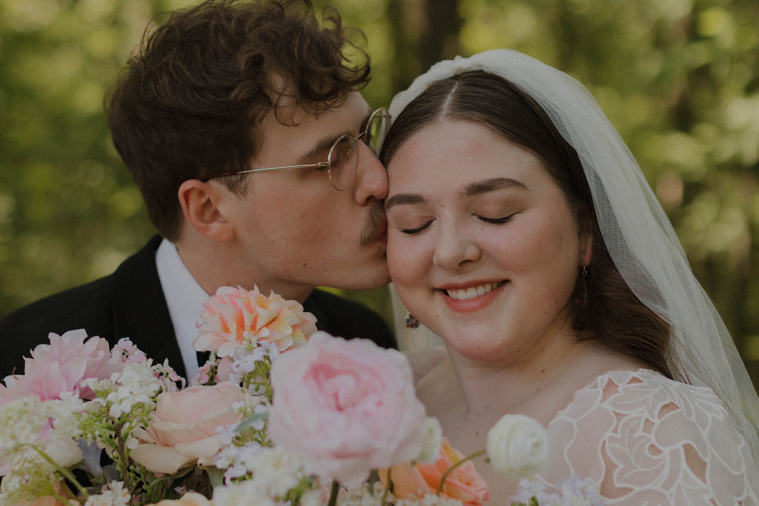 A romantic wedding moment with pink roses and peonies in a lush outdoor garden setting.