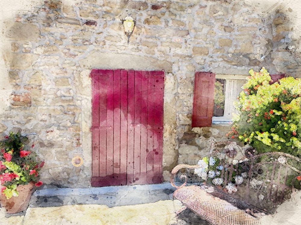 Rustic stone Tuscan cottage with red wooden door and colorful garden flowers.