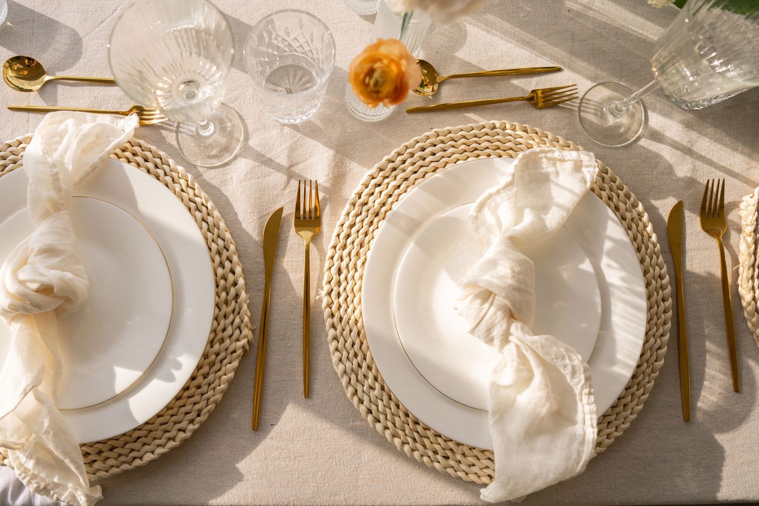 Elegant place settings with gold-rimmed plates and white linens create a luxurious dining table display.