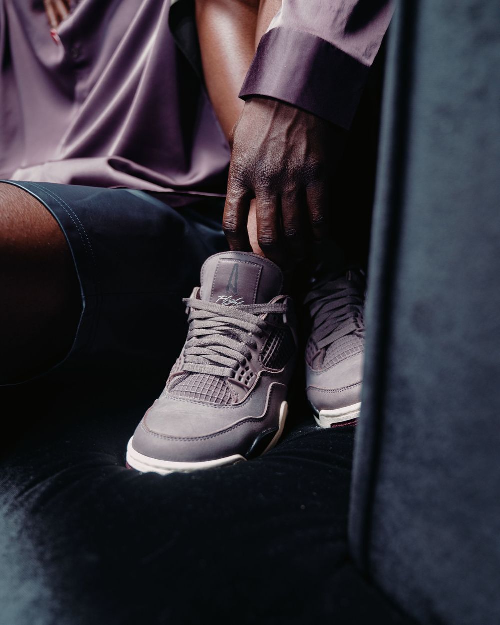 Close-up shot of gray sneakers with gum soles in moody lighting.