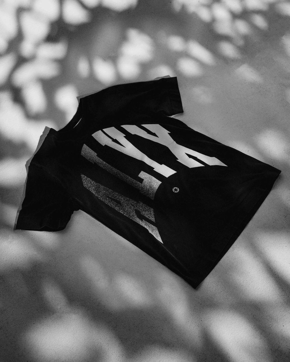 Black t-shirt with zebra stripe design photographed in dappled shadows.