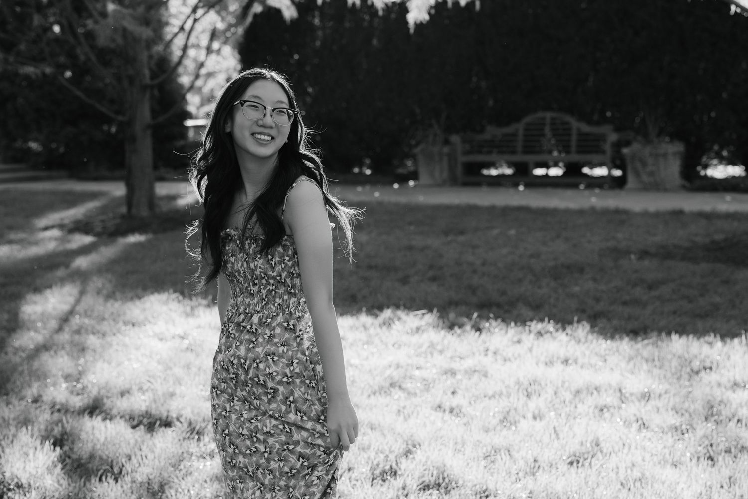 Black and white portrait of person in floral dress outdoors in natural lighting.