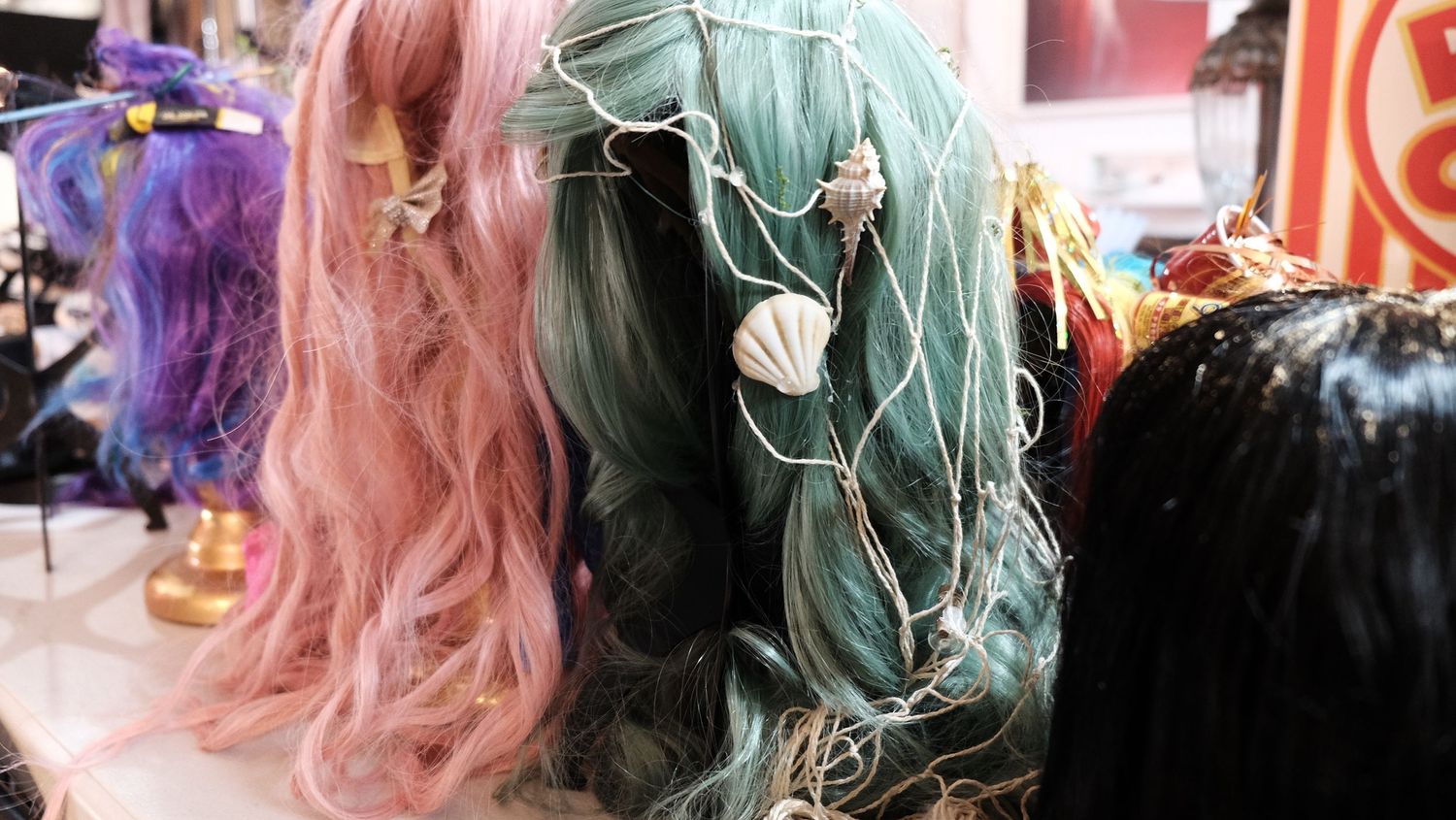 Two people in costumes pose together under pink lighting at what appears to be a Halloween or cosplay event.