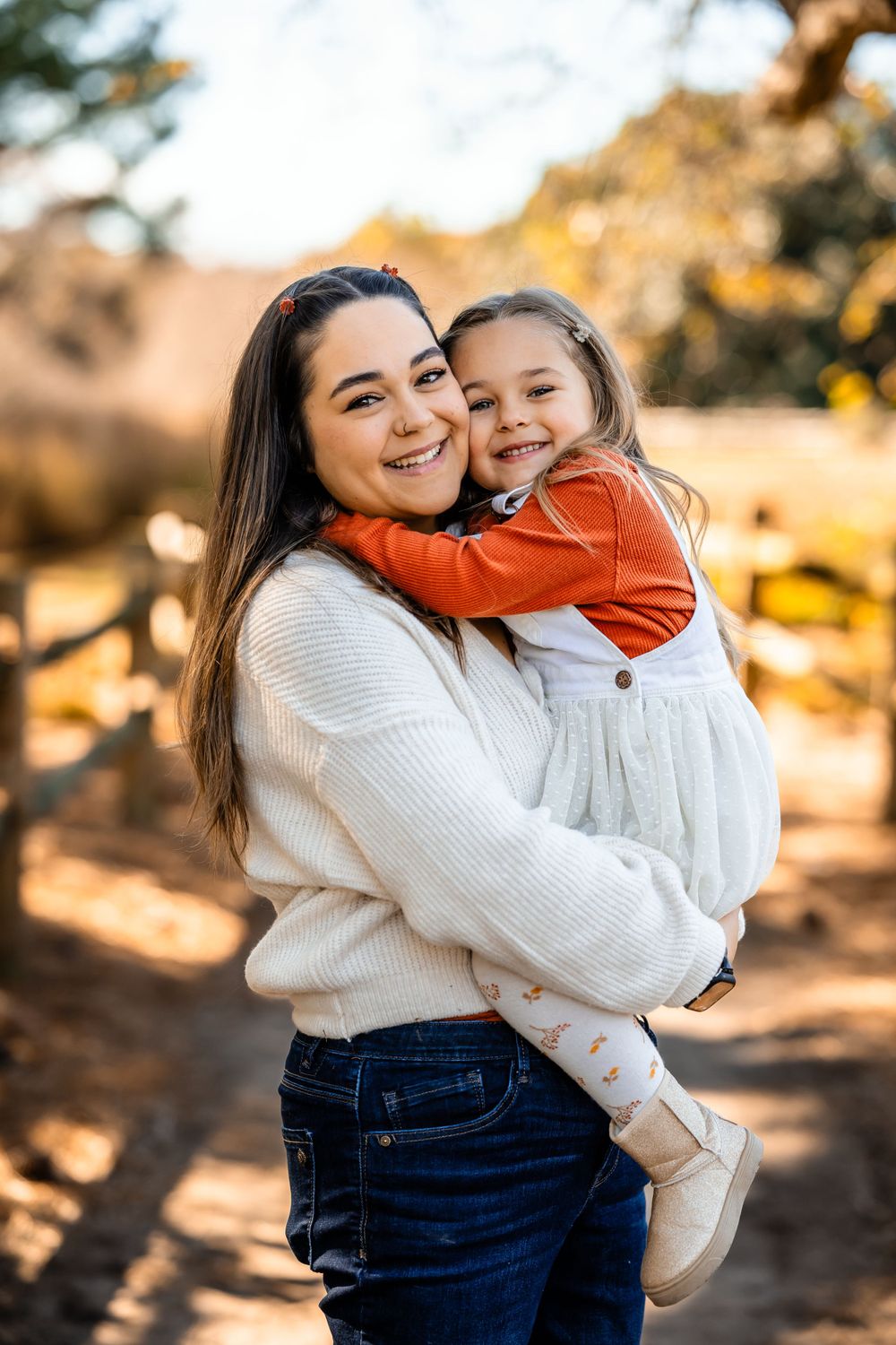Parent and child share a warm embrace while wearing cozy sweaters in an autumn outdoor setting.