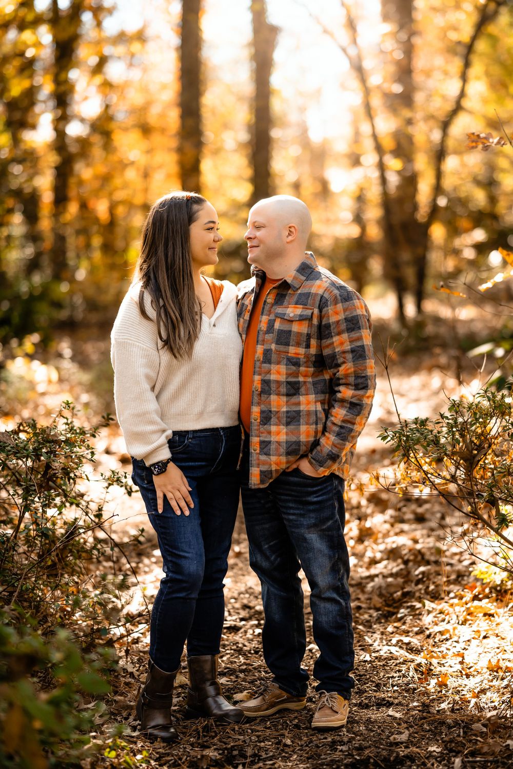 Couple sharing a loving moment on wooded trail during golden hour autumn light.