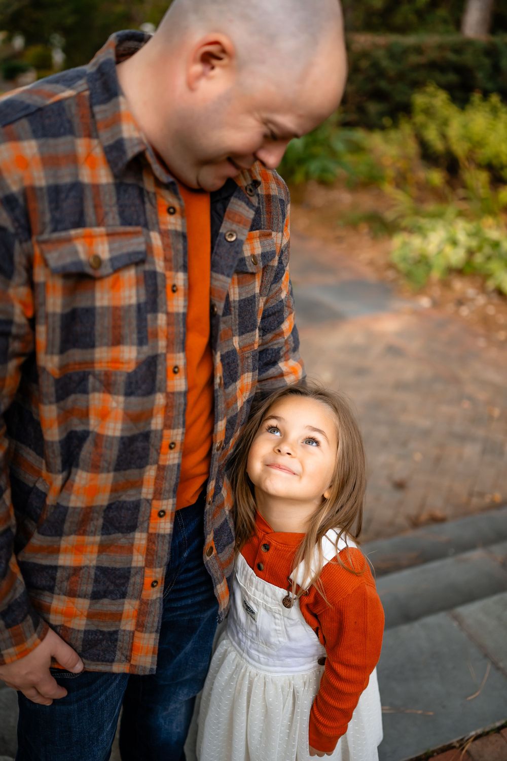 A heartwarming moment between parent and child in matching orange autumn outfits on a garden path.